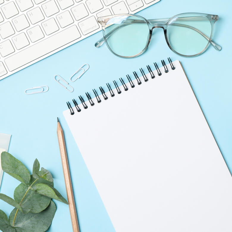 blue background with note pad, pencil, keyboard and paperclips